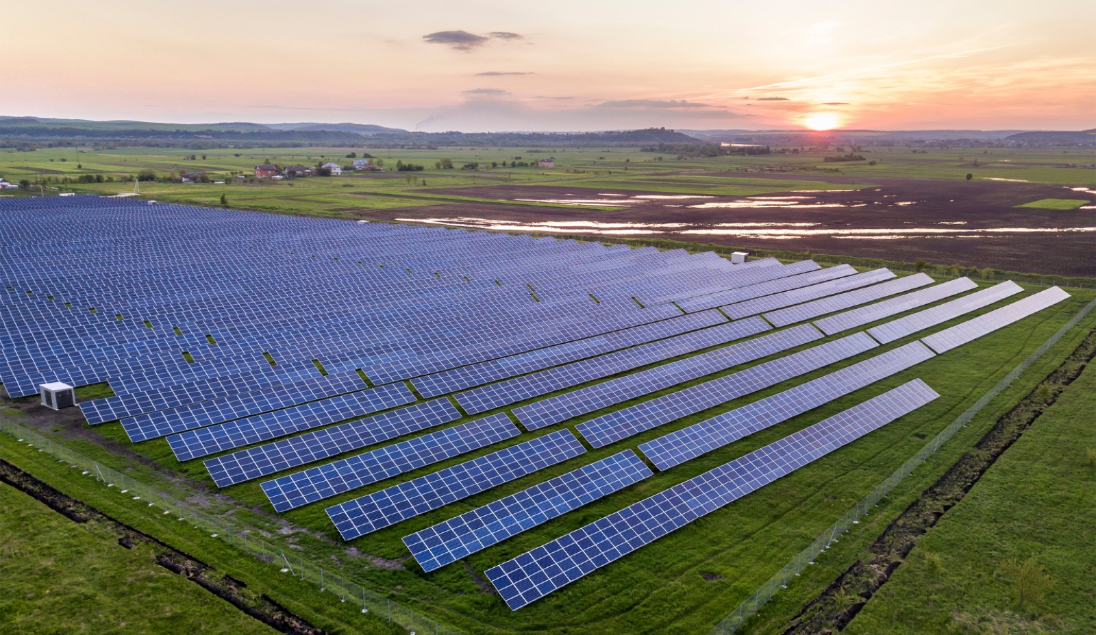 Large rooftop and ground-mount solar array at sunset